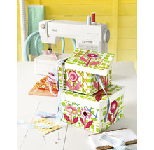 Scène de couture avec machine à coudre, tissus, boutons, rubans et boîtes de rangement décorées