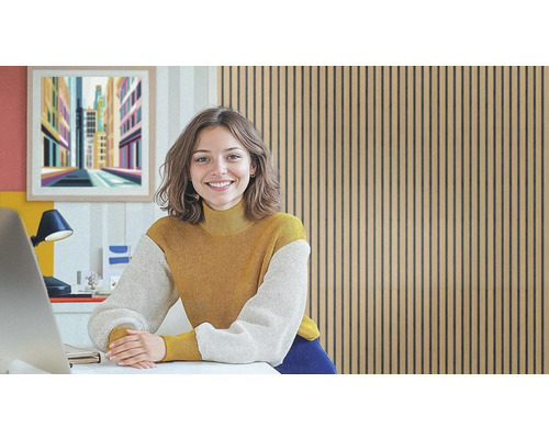 Frau lächelt an einem Schreibtisch vor einer Wand aus Holzpaneelen.