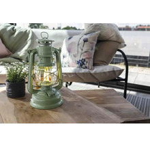 Lanterne décorative sur une table en bois avec plante en pot et coin salon en arrière-plan.