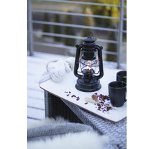 Nature morte avec lampe à pétrole, gants et boissons sur une table à l''extérieur.