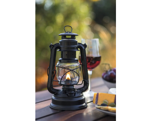 Lampe à pétrole noire sur une table en bois avec des collations et des boissons