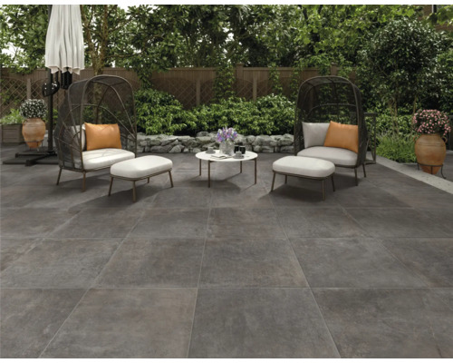 Terrasse mit Bodenplatten, Sitzgruppe und Sonnenschirm im Garten.