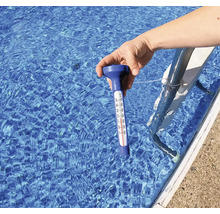 Hand hält Poolthermometer ins Wasser