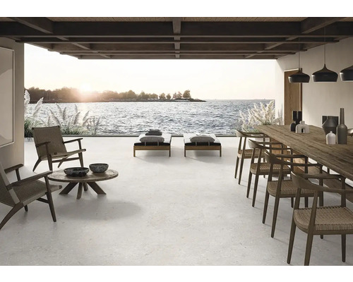 Grosse Terrasse mit Fliesenboden, Liegestühlen, Tisch und Stühlen mit Meerblick.