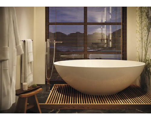 Freistehende Badewanne auf Holzrost in einem Badezimmer mit Fenster und Jalousien