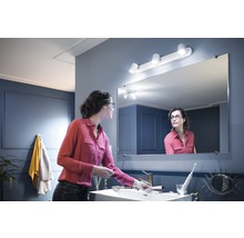 Femme dans salle de bains avec armoire de toilette et éclairage