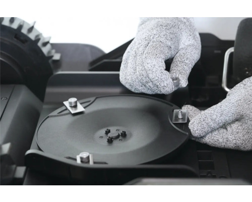 Installation du disque à couteaux sur un robot de tonte avec des gants de protection