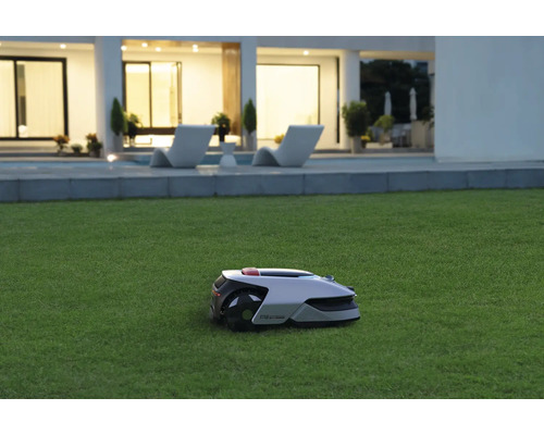 Robot tondeuse sur une pelouse devant une maison