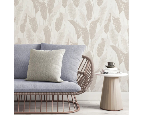 Szene mit Sofa, Kissen, Beistelltisch und Tapete mit Blättermuster.
