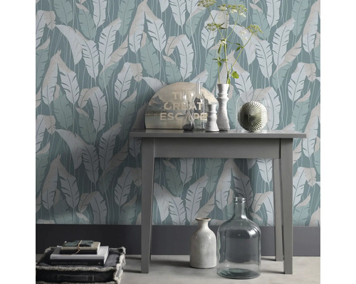 Dekoratives Interieur mit einer Tischkonsole vor einer Blattmuster Tapete
