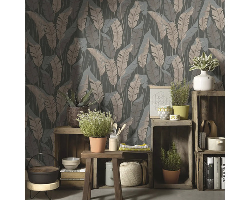Dekoratives Zimmer mit einer Tapete mit Blattmuster und Pflanzen auf Holzkisten.