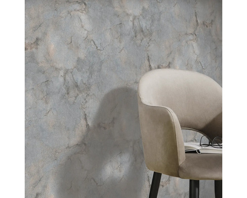 Szene mit einer Wandgestaltung in Marmoroptik und einem Sessel mit Buch und Brille.