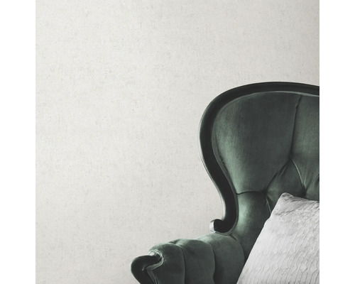 Detailaufnahme eines grünen Sessels mit Kissen vor einer Wand