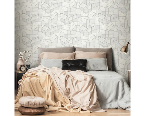 Schlafzimmer mit Bett und geometrischer Tapete im Hintergrund