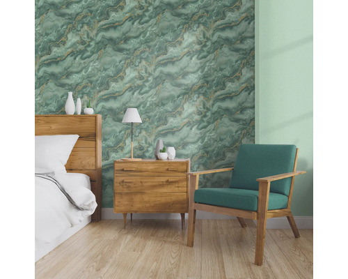 Chambre avec lit, table de chevet et fauteuil devant un mur avec papier peint marbré.