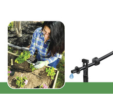 Frau pflanzt Blumen in einem Garten mit einem Tropfbewässerungssystem.