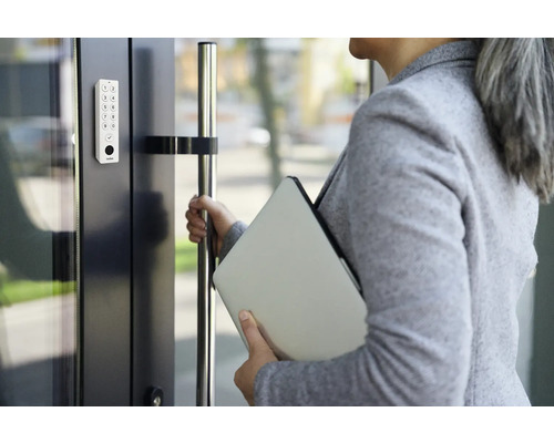 Femme ouvre la porte avec une serrure à code numérique