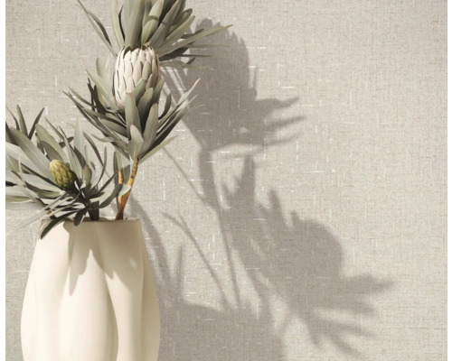 Fleur de protéa dans un vase devant un papier peint