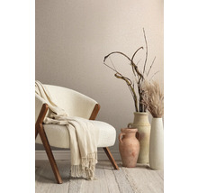Dekoratives Interieur mit Sessel, Decke, Vasen und Ziergräsern vor einer Wand mit Textiltapete.