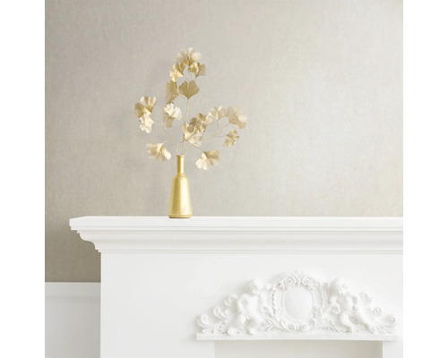 Nature morte décorative avec vase doré et branches de ginkgo sur une cheminée blanche.