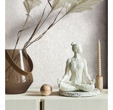 Scène décorative avec une figurine de yoga, un vase avec des graminées ornementales, une boule et une bougie sur une commode blanche.