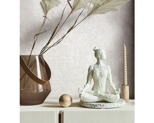 Dekorative Szene mit einer Yogafigur, einer Vase mit Ziergras, einer Kugel und einer Kerze auf einer weißen Kommode.