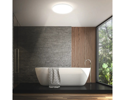 Modernes Badezimmer mit freistehender Badewanne, gemauerter Wand und runder Deckenleuchte