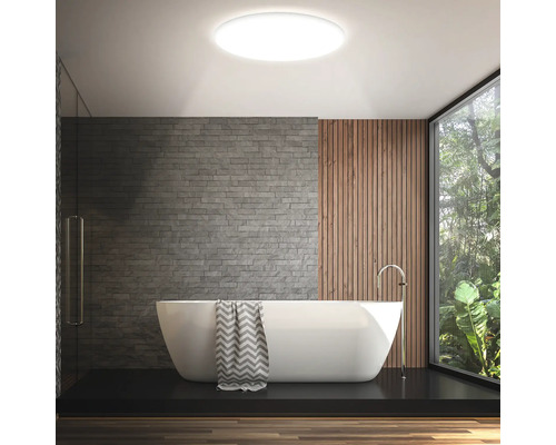 Salle de bains avec baignoire, mur en pierre, lambris en bois et plafonnier rond