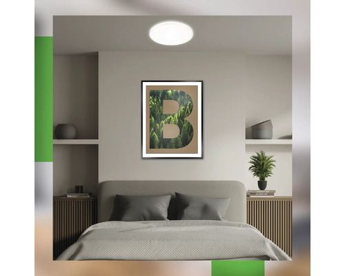 Schlafzimmer mit Bett, Nachttischen, Wandregalen, Deckenleuchte und einem gerahmten Buchstaben B Bild an der Wand