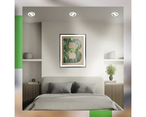Chambre avec un lit et une image encadrée représentant une forêt verte disposée en forme de lettre B