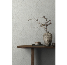 Vue détaillée d''un mur décoré avec du papier peint à motifs floraux, une table en bois avec des décorations et un vase avec des branches.