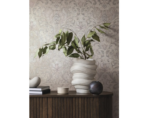 Dekoratives Interieur mit gemusterter Tapete, Kommode, Büchern und Vasen