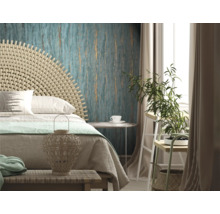 Helles Schlafzimmer mit Bett, Rattan-Kopfteil, gemusterter Tapete und Zimmerpflanze