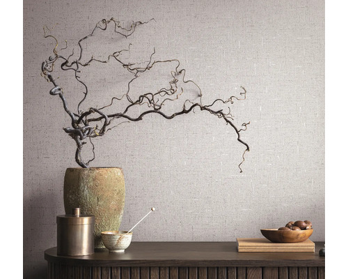 Nature morte décorative avec vase, branches, bol et table en bois devant un mur texturé