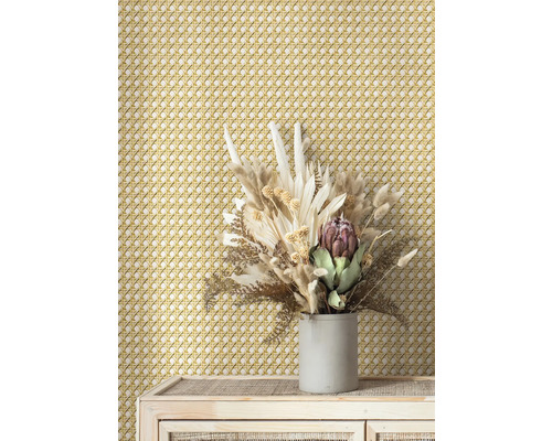 Dekorative Wand mit Rattanmuster und Trockenblumenarrangement auf Kommode