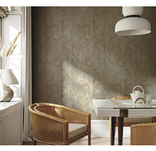 Wohnzimmer mit Wandfliesen in Steinoptik, Rattansesseln und Esstisch mit Teegeschirr.