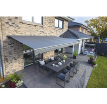 Terrasse mit Markise, Esstisch und Gartenmöbeln an einem Backsteinhaus