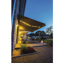 Terrasse mit Markise, Tisch und Stühlen bei Dämmerung