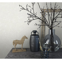 Arrangement décoratif avec vase, branches, figurine de cheval et pinceaux sur une table.