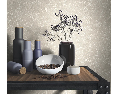 Scène décorative avec vases, bol et branches sur une table devant un papier peint mural.