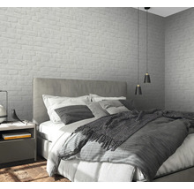 Chambre avec lit, table de chevet et papier peint mural à motif de maçonnerie.
