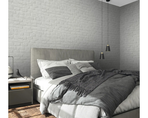 Chambre avec lit, table de chevet et papier peint mural à motif de maçonnerie.