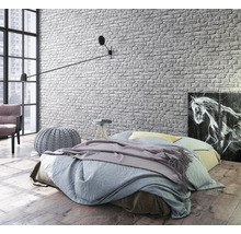 Chambre lumineuse avec lit, applique murale et papier peint en briques