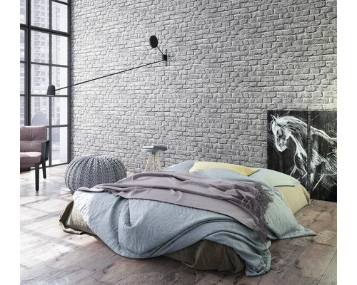 Chambre lumineuse avec lit, applique murale et papier peint en briques