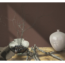 Nature morte décorative avec vase, branches et tissu sur une table en bois devant un mur uni