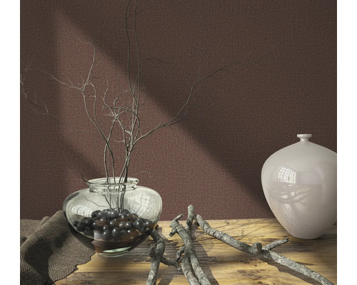 Nature morte décorative avec vase, branches et tissu sur une table en bois devant un mur uni