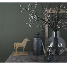 Nature morte décorative avec cheval en bois, vase, plantes et images sur une table.