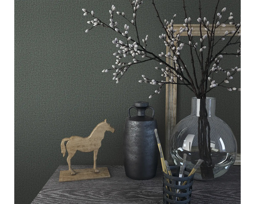 Nature morte décorative avec cheval en bois, vase, plantes et images sur une table.