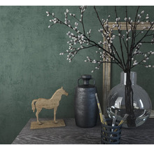 Scène décorative avec cheval en bois, vase, branches et cadre photo sur une table.