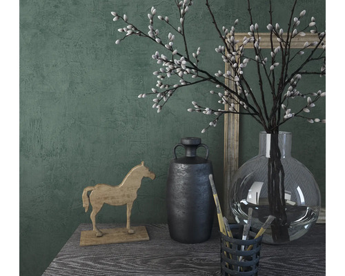 Scène décorative avec cheval en bois, vase, branches et cadre photo sur une table.